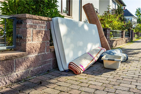 Photograph of a matress and rolled up carpet on a street